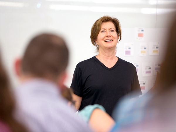 A Faculty Member lecturing to students in front of a whiteboard