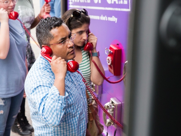 Image of participants engaging in interactive experiences on the “Check Your Blind Spots” bus tour include a phone bank, “Wake Up Call: Listen to Someone Else’s Reality.”
